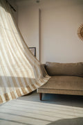 Striped linen sheer curtains in beige and white hanging in coastal living room with natural light filtering through
