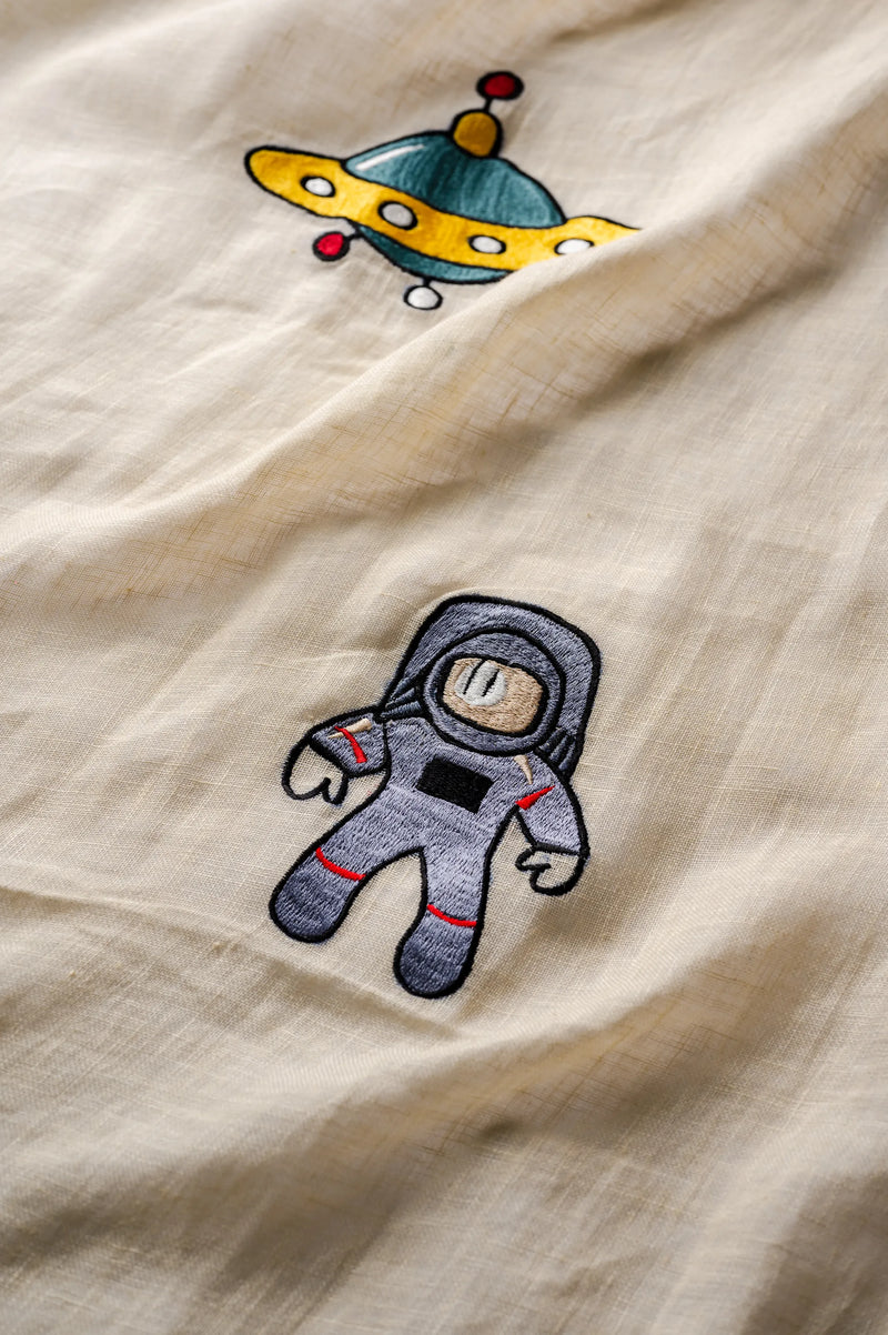 Embroidered astronaut and spaceship details on warm yellow linen nursery curtains