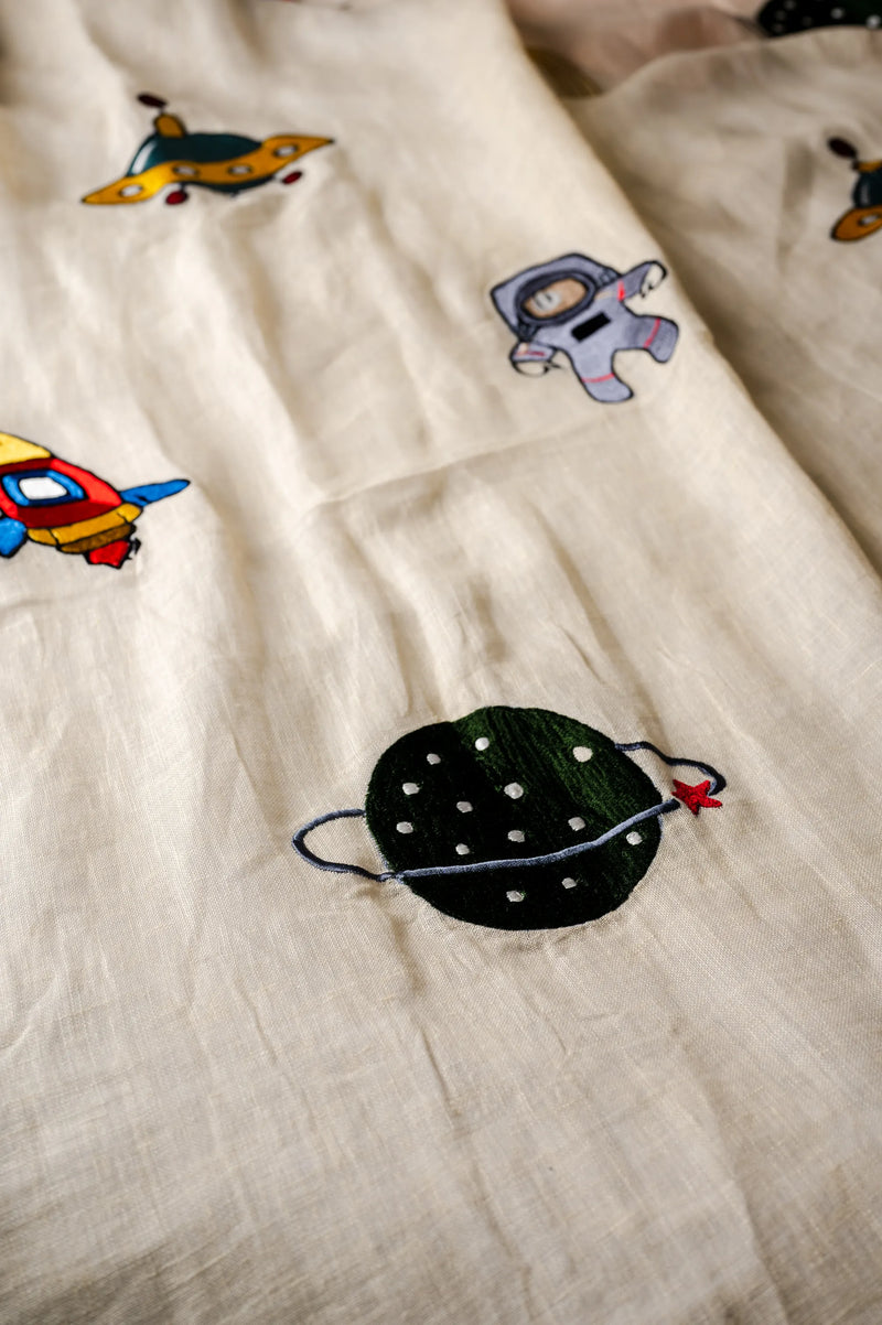 close-up detail of hand-embroidered celestial elements on yellow linen fabric showing artisan craftsmanship