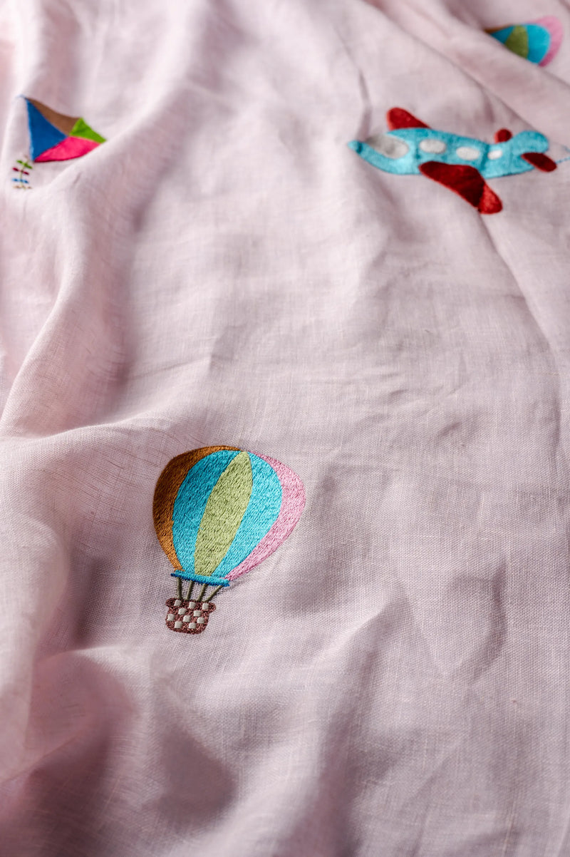 Close-up of hand-embroidered hot air balloon detail on soft pink linen nursery curtain